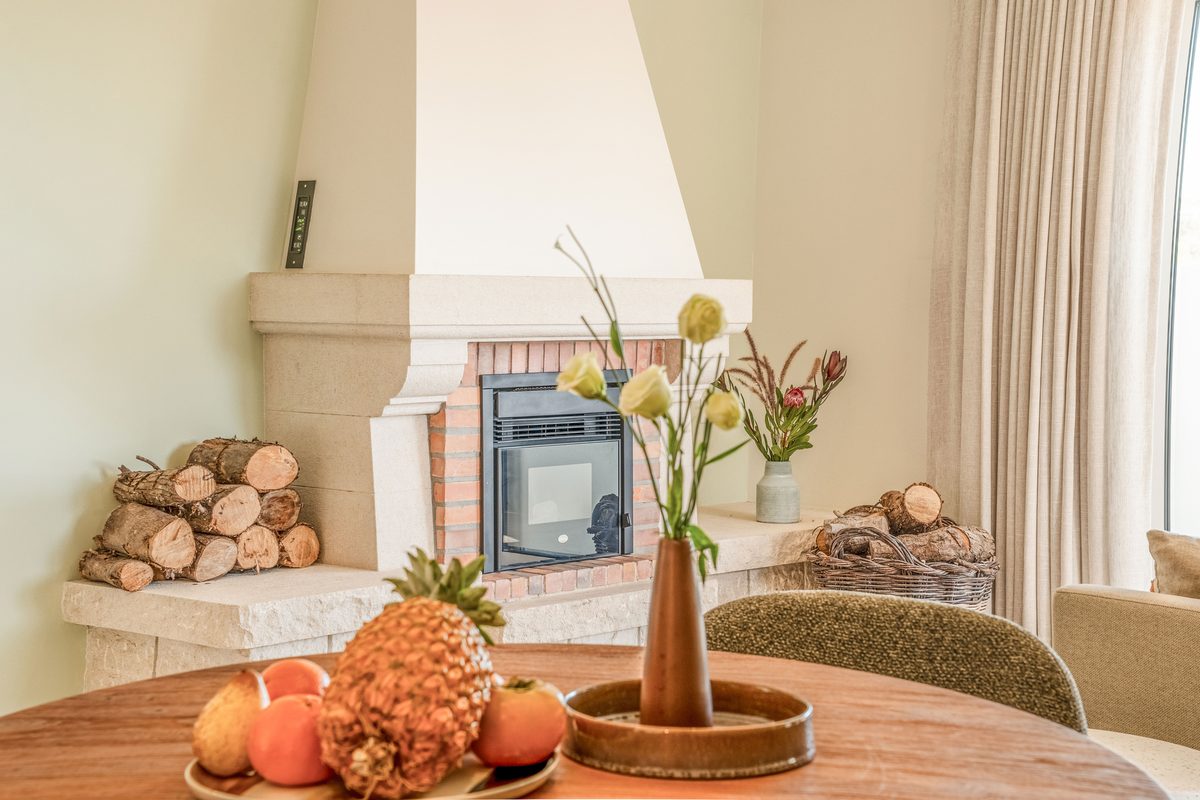Stone fireplace with logs, and the dining table in front of it