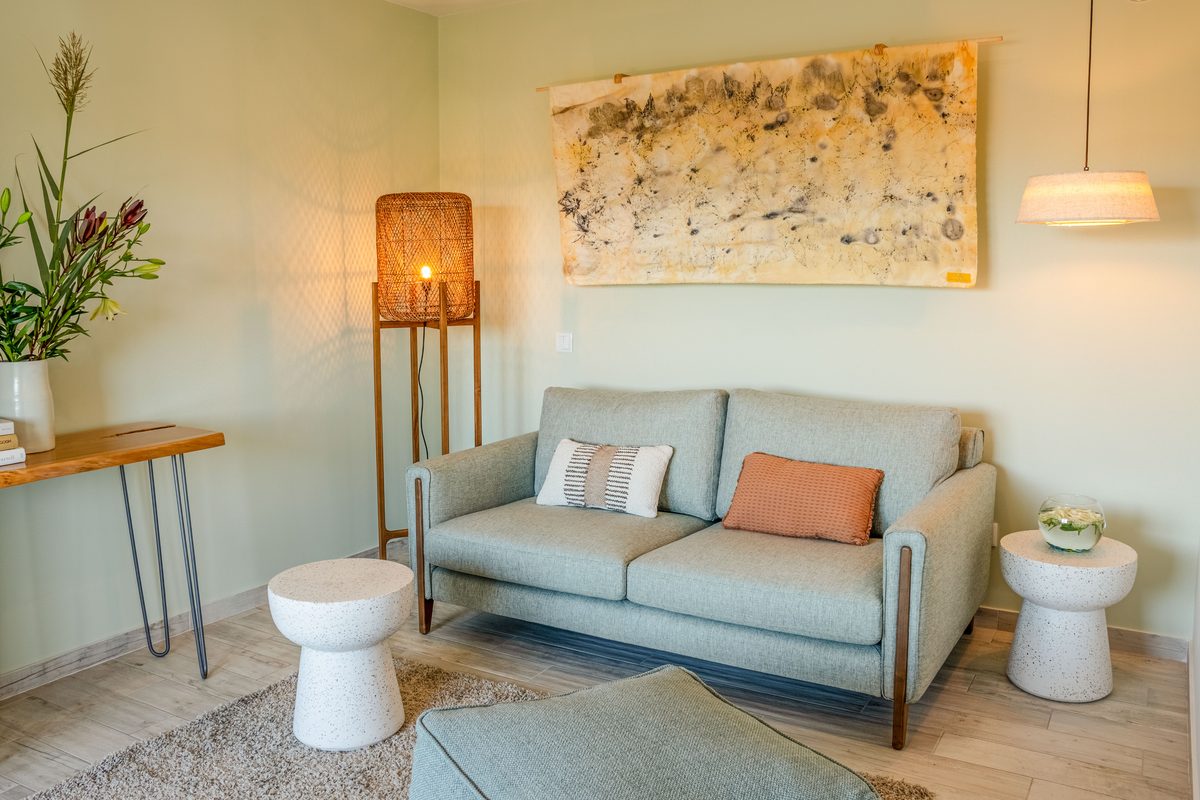 Sitting area with a pale blue sofa, floor lamp and woven artwork