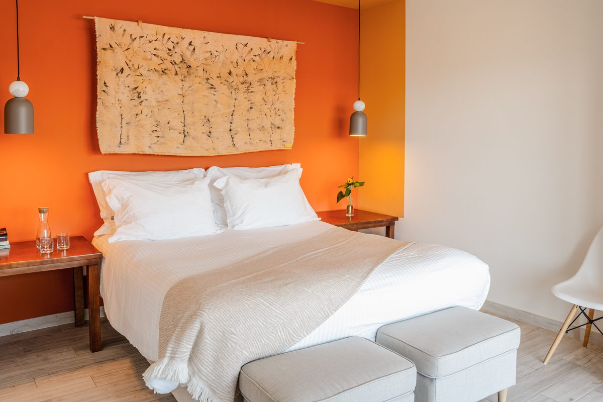 Double bed against the terracotta wall, bark artwork above it