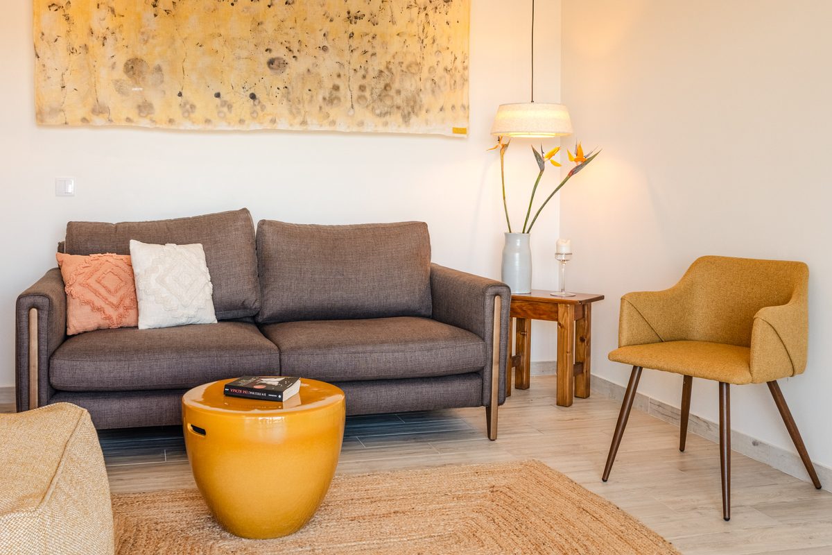 Sitting area with a grey sofa, mustard armchair and yellow pouffe
