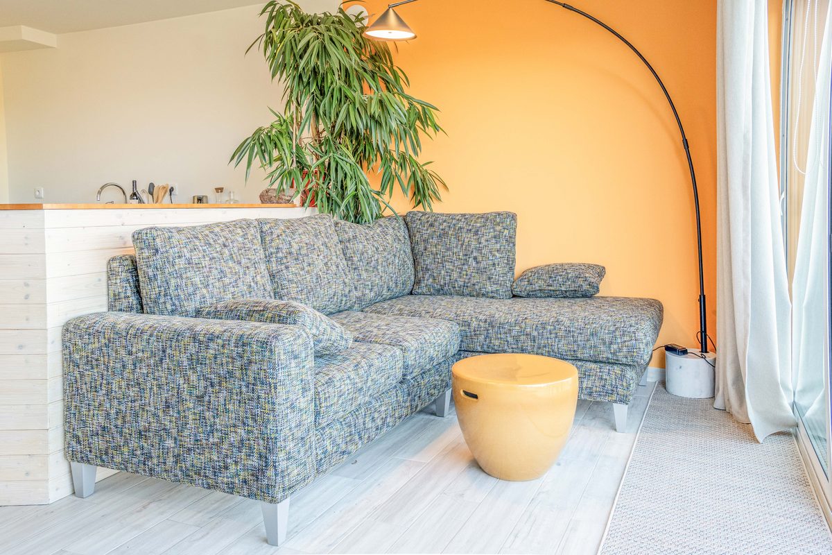 Sitting area with a patterned sofa, arc lamp and pouffe