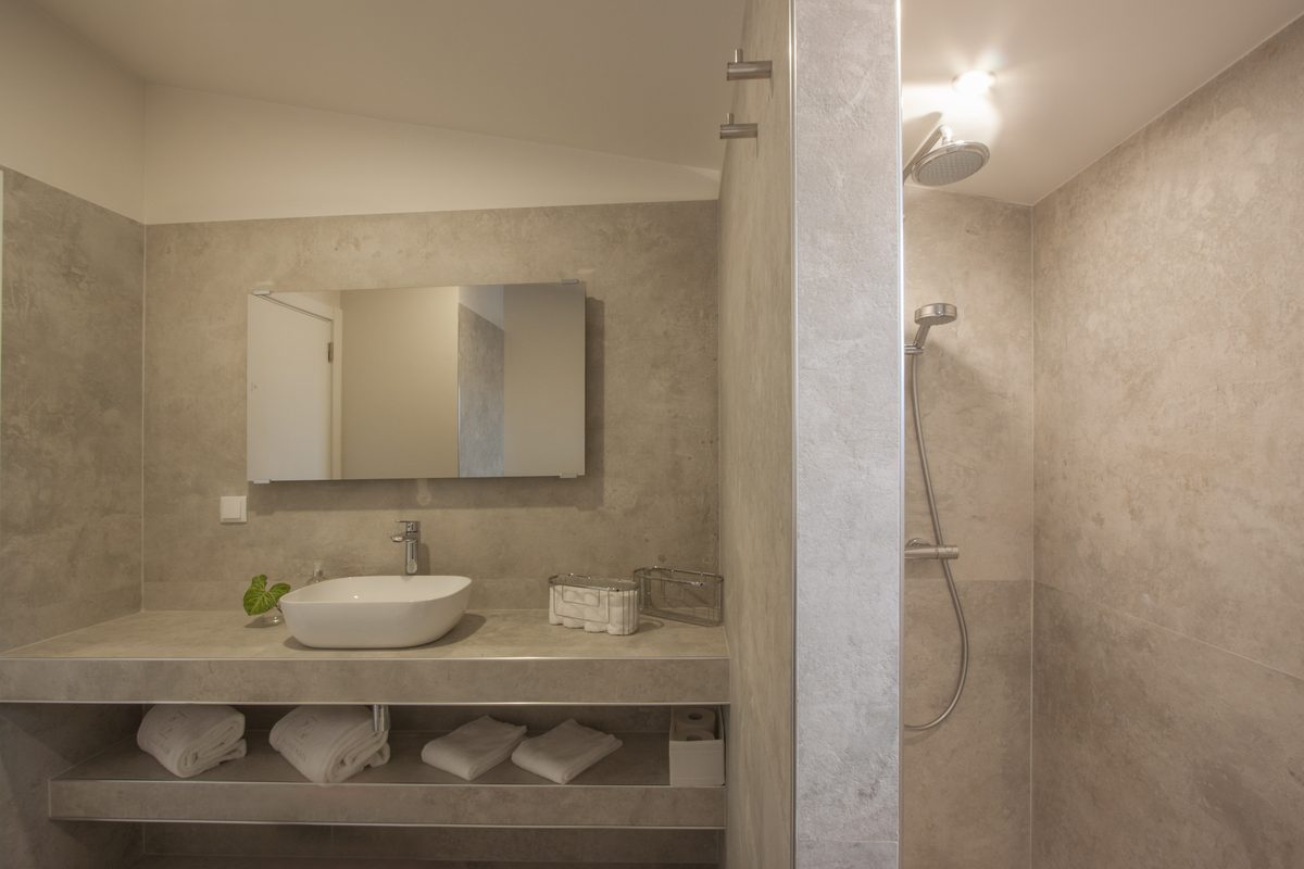 Bathroom in microcement, with a vessel basin and a walk-in rain shower